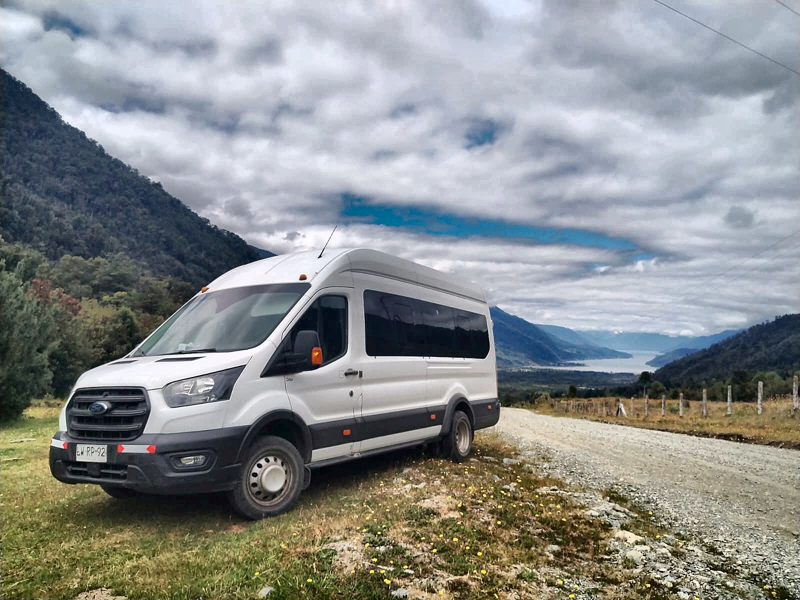 Ford Transit de Transportes DANES en un camino con vista al lago y la cordillera